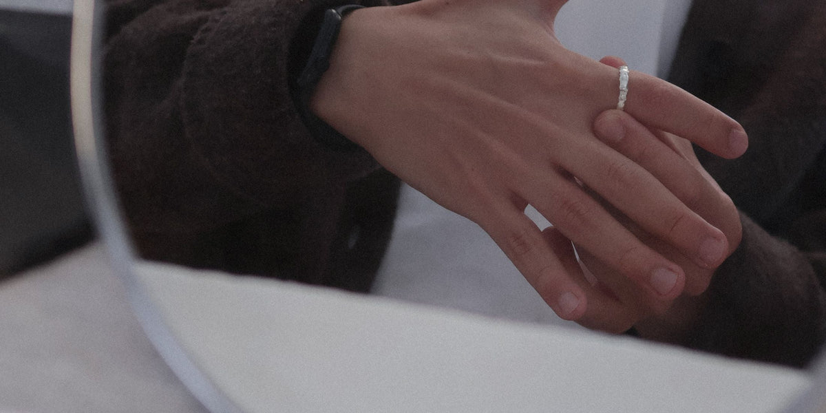 A hand-poured sterling silver band worn on the ring finger, seen in soft daylight