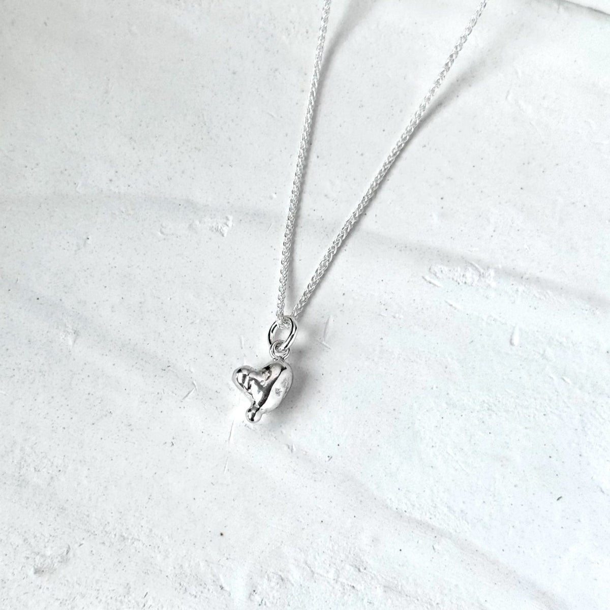 Molten Heart pendant, textured sterling silver heart on a white background