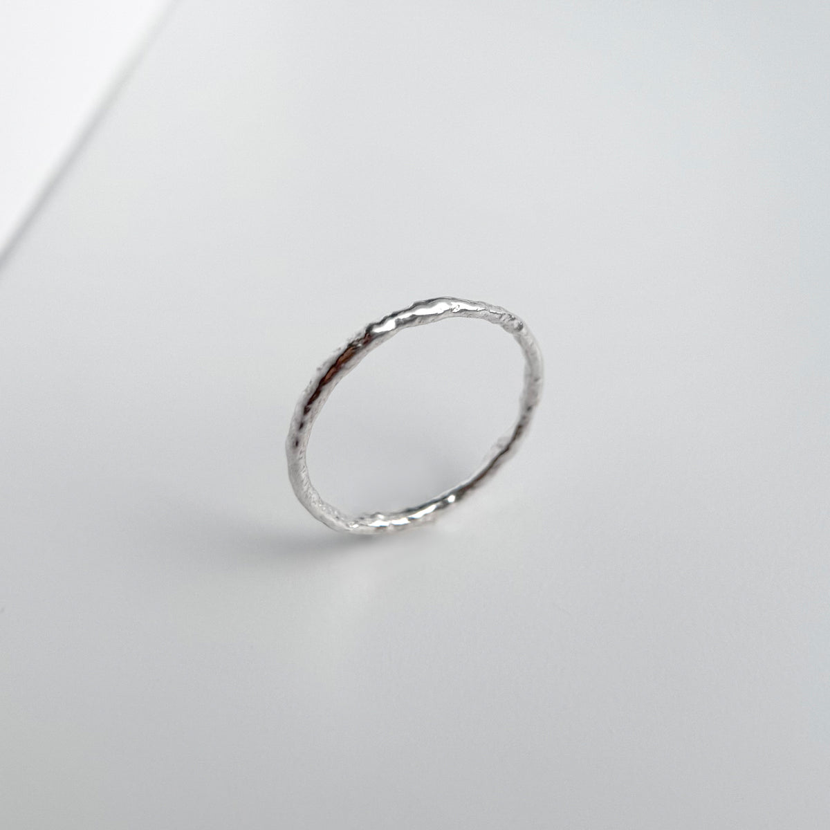 Molten Line Ring, a thin sterling silver band with an uneven hand poured molten texture