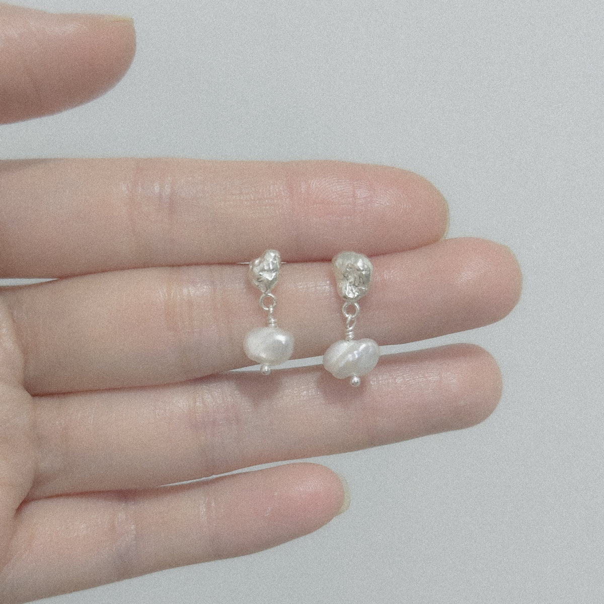 Molten Pearl Earrings held in the hand
