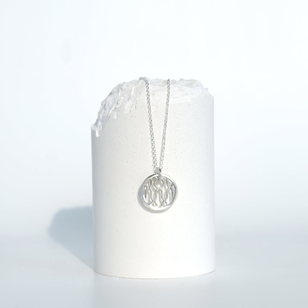 Helix Sentinel Necklace, a round sterling silver pendant with an open helix lattice cut through it